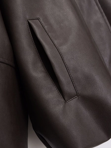 Close-up of deep brown faux leather jacket showing pocket detail and precise stitching
