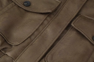 Detailed macro view of dark brown jacket pocket featuring precise stitching and black button
