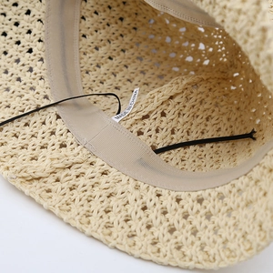 Detail of beige hollow woven sun hat featuring sweatband and elastic inner chin strap