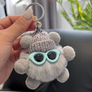 Porte-clés peluche noiraude grise avec bonnet et lunettes de soleil en main