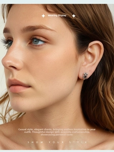 Close-up of retro silver scorpion stud earrings with dark gemstone inlay on ear