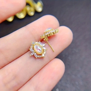 Macro shot of oval moonstone earrings with marquise zircon stones in gold floral cluster