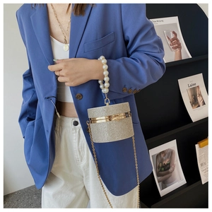 Detail of silver rhinestone cylinder evening bag with white pearl handle and metal chain