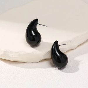 Minimalist black teardrop stud earrings with high-gloss finish on white stone background