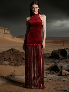 Elegant dark red velvet halter dress with fringe hem on a desert background