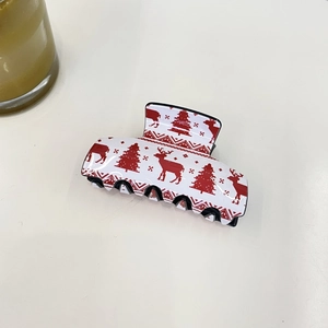 Detail of white Christmas hair claw clip featuring red reindeer and snowflake patterns