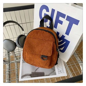 Detail of a brown corduroy mini backpack inside a metal cart with urban lifestyle items