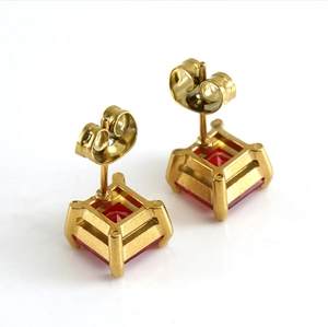 Détail de boucles d'oreilles carrées dorées avec pierres rouges et fermoir papillon