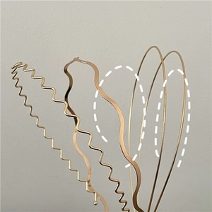 Close-up of assorted gold metal wave headbands with polished finish and elegant texture