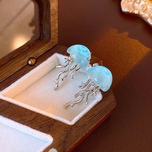 Vue détaillée de boucles d'oreilles méduses bleues avec cristaux sur un coffret en bois