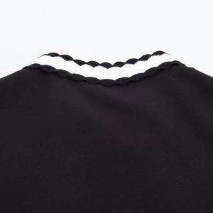 Détail d'un col polo noir avec bordure décorative blanche ondulée et texture en maille
