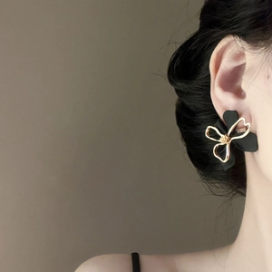 Detail view of model wearing double-layer hollow black flower earrings with gold edges