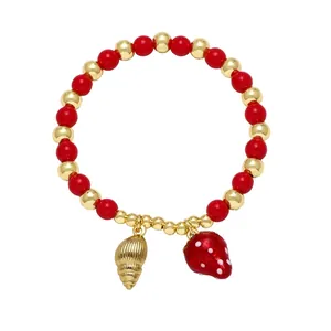 Beaded gold and red strawberry bracelet with shell charm on pure white background