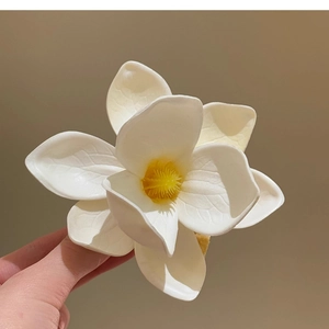 Close-up of plumeria hair clip with lifelike white petals and yellow center detail