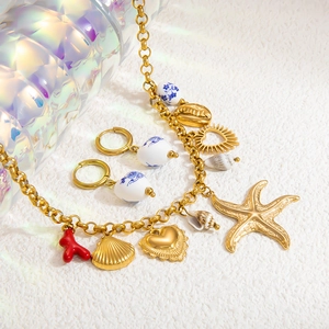 Detail of 18k gold starfish and coral charms with blue porcelain beads on jewelry set