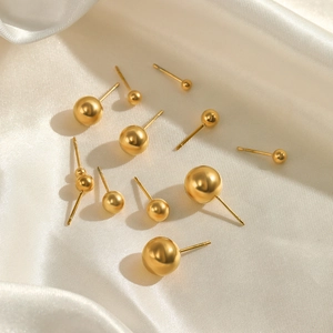 Minimalist gold ball stud earrings in various sizes displayed on white silk fabric