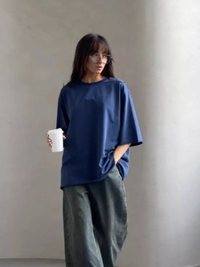 Dettaglio di una t-shirt oversize in cotone blu scuro abbinata a pantaloni grigi larghi