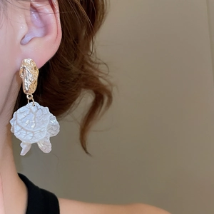 Close-up of petal tassel earrings with hammered gold metal and textured white resin