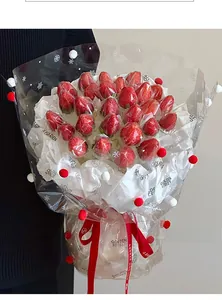Close-up of strawberry gift bouquet with snowflake pattern wrap and fuzzy pom pom trim