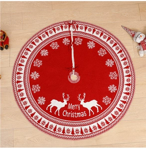 Detail of red knitted Christmas tree skirt with white reindeer and Merry Christmas text