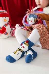 Detail view of blue coral fleece Christmas socks with snowman pattern on festive background