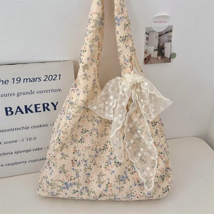 Detail of floral canvas tote bag featuring a delicate white lace bow decoration