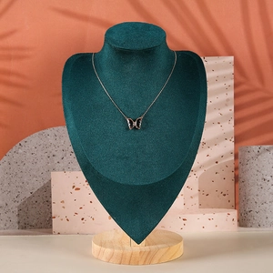 Macro detail of butterfly pendant necklace displayed on dark green velvet neck mannequin