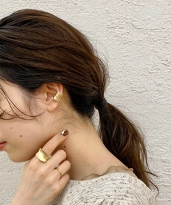 Nahaufnahme eines mattgoldenen, unregelmäßigen Ohrmanschetten- und Ringsets am Model