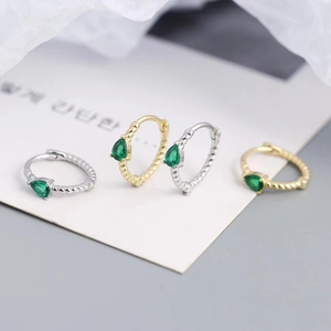 Macro shot of twisted S925 silver hoop earrings with pear-cut emerald zircon stones