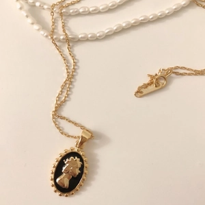 Macro detail of gold Elizabeth II oval pendant with S925 engraving and black background