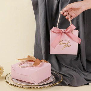 Detailed view of pink wedding gift bag with golden rope handle and satin ribbon bow