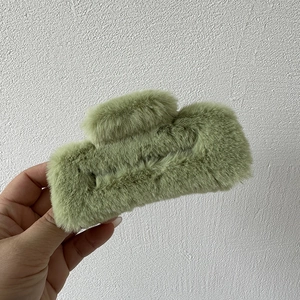 Close-up of green plush rectangular hair claw clip with soft faux fur texture for women