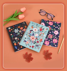 Detailed top view of three A5 spiral notebooks with floral covers and stationary accents