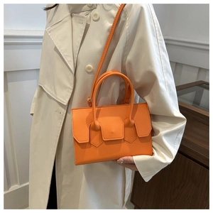 Detail of orange leather handbag with top handles and detachable shoulder strap