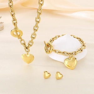 Macro view of gold stainless steel heart jewelry set with chunky chains and T-bar clasps
