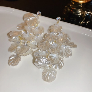 Detail of flower petal earrings with pearl luster, gold tassel and shiny rhinestones