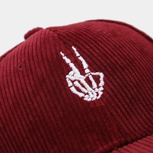 Macro shot of white skeleton hand embroidery on high-quality burgundy corduroy cap