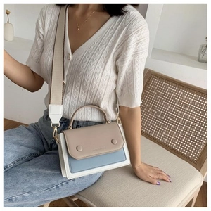 Detail of multi-color patchwork shoulder bag with stylish wide fabric strap on model