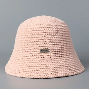 Detailed macro view of the hand-knitted texture and silver metal tag on a pink bucket hat
