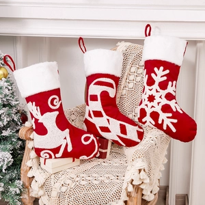 Three embroidered Christmas stockings with reindeer and snowflake patterns on a cozy wood chair