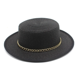 Gros plan d'un chapeau de paille noir avec une chaîne dorée décorative de style moderne
