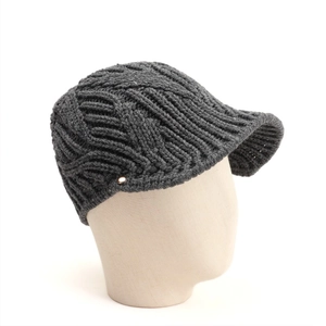 Detail of dark grey cable knit visor beanie with minimalist round metal logo accent