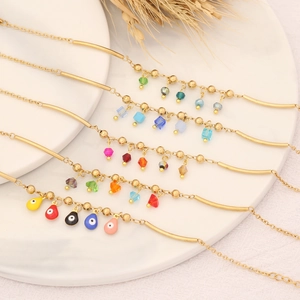 Ensemble de bracelets dorés avec cristaux colorés et breloques œil sur un plateau blanc