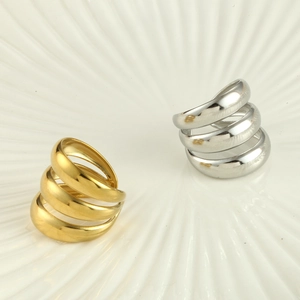 Nahaufnahme goldener und silberner Spiralringe auf weißer Keramikschale mit Hochglanz
