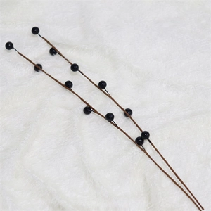 Detailed close-up of decorative artificial black berry branches on a white plush background