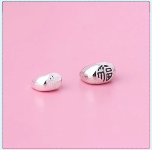 Detailed macro view of S925 sterling silver bean charms with Fu character engraving