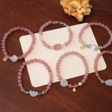 Close-up of pink crystal bead bracelets with gold charms and elegant pearls on wood