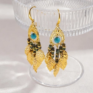 Détails de boucles d'oreilles vintage dorées avec perles turquoise et feuilles sur verre