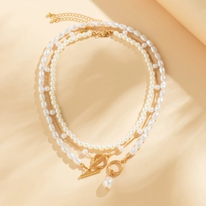 Detailed view of triple-layered pearl necklace with baroque pearls and golden OT clasp