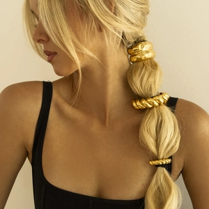 Close-up of golden metallic hair ties with wave and twisted textures on a ponytail